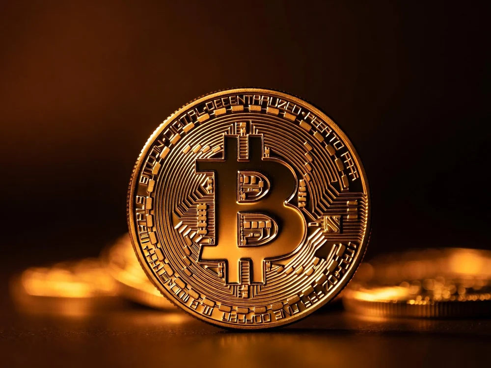 一枚刻着比特币标志的实体金币，象征 2100 万枚的稀缺上限
